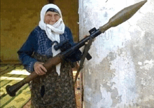 an elderly woman holding a large rocket launcher in front of a wall that has the word " oui " on it