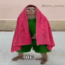 a monkey wearing a pink towel and green shorts is standing on a tiled floor .