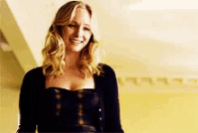 a woman in a black dress is smiling and looking at the camera .