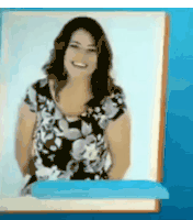 a woman in a floral dress is smiling in front of a blue wall .