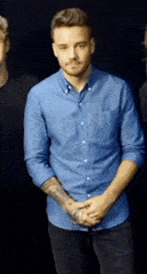 a man in a blue shirt has a tattoo on his left arm