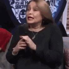 a woman is sitting on a couch holding a cell phone and making a funny face