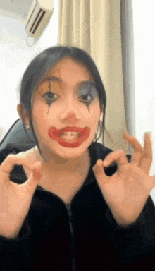 a woman is wearing a clown costume and making a peace sign with her hands .