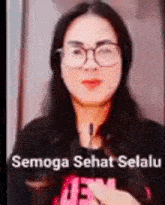 a woman wearing glasses is holding a microphone in her hand .