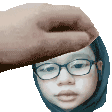 a hand is holding a person 's head with glasses and a hijab .