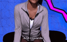 a woman in a grey jacket is sitting on a couch and saying and cowards