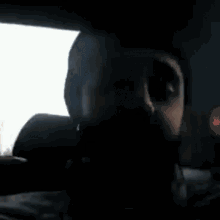a man with a beard is sitting in a car and looking at the camera