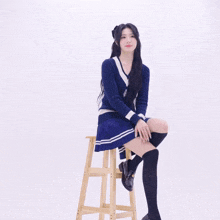 a girl is sitting on a wooden stool with her legs crossed