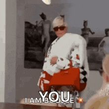 a woman is holding a red purse and saying `` i am your '' .