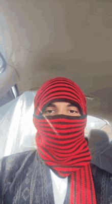 a man wearing a red and black striped scarf around his face
