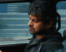 a man is sitting in a car looking out the window