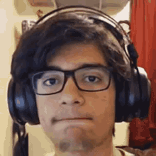 a man wearing headphones and glasses is making a face .