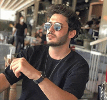 a man wearing sunglasses and a black shirt is sitting at a table