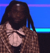 a man with dreadlocks is wearing a plaid jacket