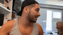 a man with a beard wearing a tank top and a black hat