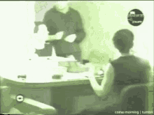 a man is standing next to a woman sitting at a table in a room .