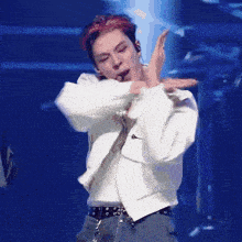 a man in a white jacket and blue pants is dancing on a stage .