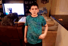 a boy in a blue shirt stands in front of a television