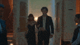 a woman in a black dress is walking with a man in a black suit