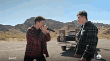 two men singing in front of a truck with nbc written on the bottom