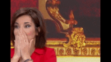 a woman in a red dress is covering her face with her hands .
