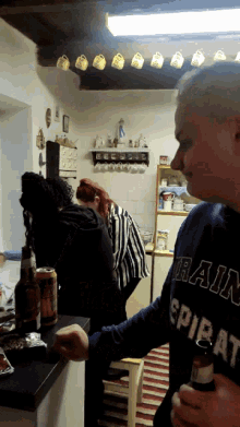 a man wearing a rain sweatshirt holds a beer bottle