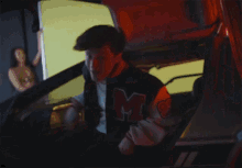 a man wearing a jacket with the letter m on the back