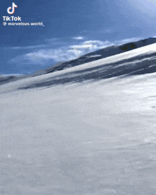 a snowy mountain with a blue sky and a tiktok logo