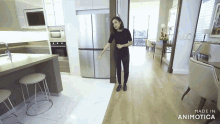 a woman standing in a kitchen next to a stainless steel refrigerator