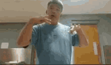 a man in a blue shirt is making a funny face in a room .