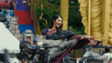 a woman in a sari is surrounded by pigeons flying around her