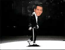 a man in a black suit is dancing on a white stage