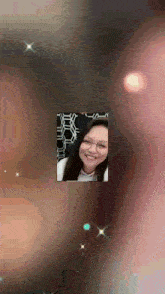 a picture of a woman with glasses is surrounded by sparkles