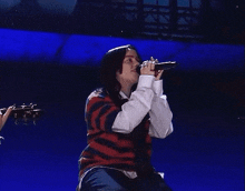 a woman is singing into a microphone while sitting on a stage .