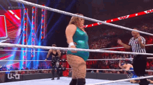 a woman in a blue leotard is in a wrestling ring with a referee .