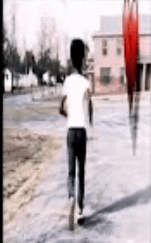 a man in a white shirt is walking down a sidewalk .