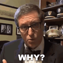 a man wearing glasses and a bow tie says " why "