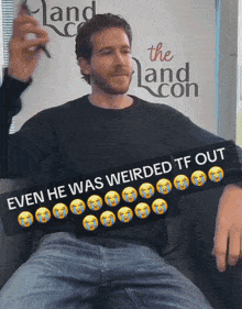 a man sitting in front of a sign that says the land con