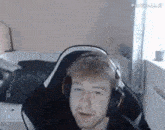 a man wearing headphones is sitting in a chair in a bedroom .