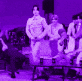 a group of people are gathered in a dark room with purple lighting