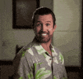 a man in a hawaiian shirt is smiling and looking at the camera