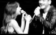 a man and woman are singing into microphones on a stage .