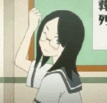 a girl wearing glasses is standing in front of a green board