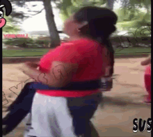 a woman in a red shirt is walking down a sidewalk with the word sus on the bottom right