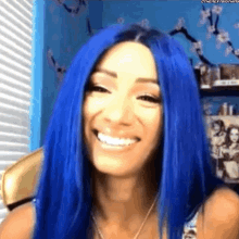 a woman with blue hair is smiling and wearing a wig .