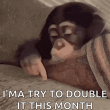 a baby chimpanzee is laying on a bed with its eyes closed and pointing at something .