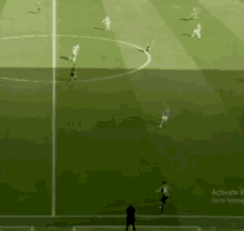 a soccer game is being played on a field with a man standing in the middle of it