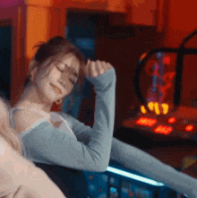 a woman is laying down with her eyes closed in front of an arcade machine