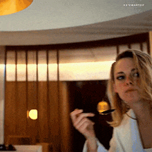a woman in a white robe is holding a knife in her right hand and looking at the camera with the words kstewartgif below her