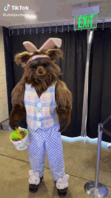 a teddy bear wearing bunny ears is holding an easter basket in front of an exit sign